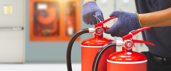 Fire extinguisher has hand engineer checking pressure gauges with exit door to prepare fire equipment for protection in emergency case and safety or rescue and alarm system training concept. - obrazy, fototapety, plakaty