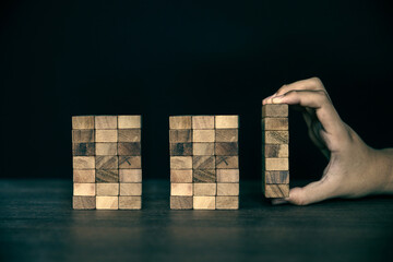 Hand placing wooden block tower stack in pyramid stair step with caution to prevent collapse or crash concepts of financial risk management and strategic planning and business challenge plan. - obrazy, fototapety, plakaty
