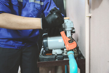 Technician plumber using a wrench to repair a water pump pipe. Concept of maintenance, fix water plumbing leaks drop or house bathroom service or cleaning clogged pipes is dirty or rusty. - obrazy, fototapety, plakaty