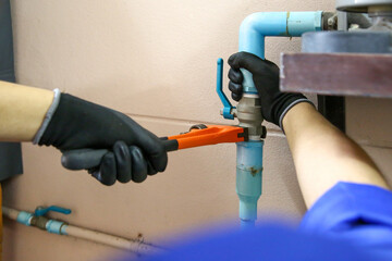 Technician plumber using a wrench to repair a water pump pipe. Concept of maintenance, fix water...