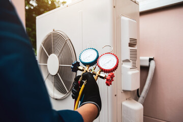 Heat and Air Conditioning, HVAC system service technician using measuring manifold gauge checking refrigerant and filling industrial air conditioner after duct cleaning maintenance outdoor compressor. - obrazy, fototapety, plakaty
