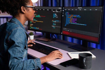Young African American IT developer concentrating on monitor screen laptop with codding program in...