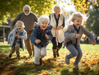 Fototapeta premium Grandparents watching their grandchildren playing in the park, laughing and playing with them.