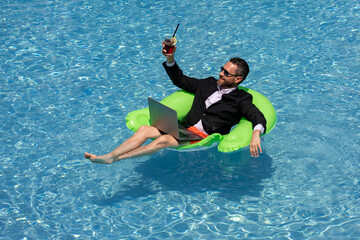 Funny businessman in suit drink summer cocktail and using laptop on the sea beach. Summer holiday,...