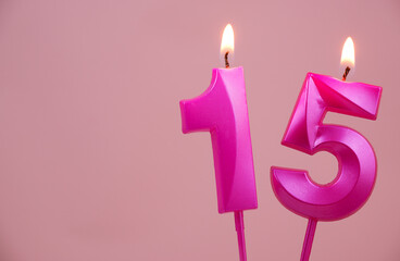 Pink birthday candles burning and melting on pink background. Copy space for text. Number 15.