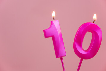Pink birthday candles burning and melting on pink background. Copy space for text. Number 10.