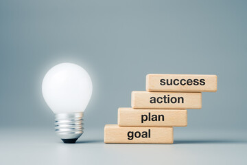 Goal, Plan, Action, and Success on step staircase symbol with glowing light bulb at the first step