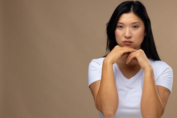 Portrait of asian woman wearing natural makeup and white t-shirt on beige background, copy space