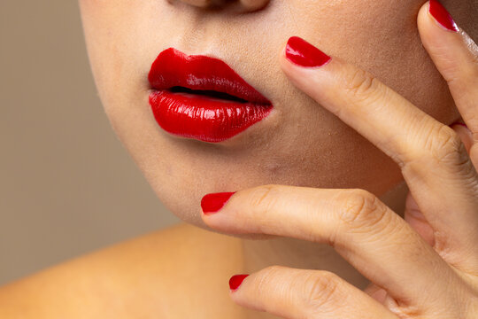 Asian Woman Wearing Red Lipstick And Nail Polish On Beige Background