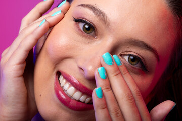 Portrait of caucasian woman wearing pink lipstick and blue nail polish on purple background