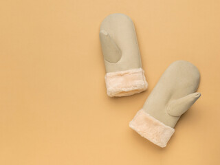Women's beige mittens on a beige background.