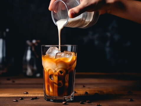 Man Hand Pouring White Milk Into A Coffee Concoction On A Brown Wooden Table To Make Dalgona Coffee