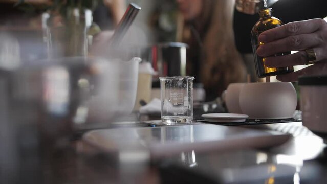 Woman's Hand Pours A Pipette Of Fragrance Perfume Into A Measuring Cup,side View