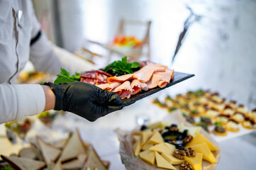 hands of a waiter hold food for a buffet table in a restaurant