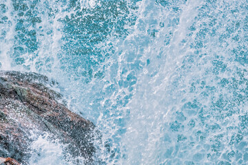Water splashes close up. Crystal clear sea water beats against the rocks. Sea waves break on the stone shore of the ocean, blue water, in pastel colors