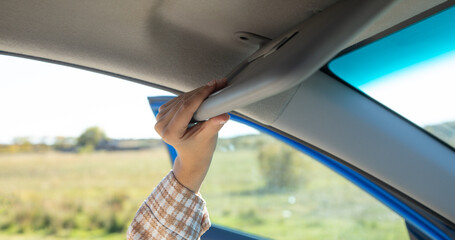 Female hand adjusting sun visor in a car.