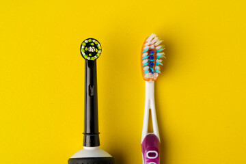 Electric and manual toothbrushes on a yellow background, close-up