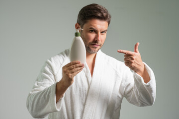 Cosmetics male products. Man with skincare products, beauty product and cosmetics isolated on gray studio background. Advertising with cosmetics bottle, spa marketing. Beauty concept.