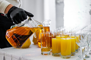 waiter pours apple juice into a glass on the buffet table