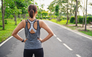 Back view of young fitness woman running on the road in the morning. People and sport concept, Sun light flare, Selective focus
