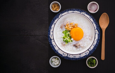 Top view of rice soup or boiled rice with pork ribs and egg in bowl on wooden table background. Thai Food