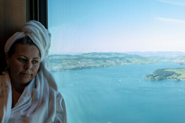 Woman in Bathrobe Enjoy the Window View over Lake Lucerne in a Sunny Summer Day in Burgenstock,...