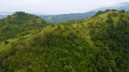Fototapeta na wymiar Forest in the mountains. Mountain range of a tropical island. Mountain tops covered with jungle. Aerial view of green hills and mountain peaks.