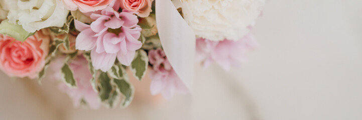 Bouquet of pink and white roses with a ribbon on a beige background. Concept for expressing love, gratitude, wedding or congratulation. Banner with copy space.