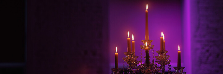 Candelabra with candles in a purple backlit background. Creepy or romantic atmosphere concept....