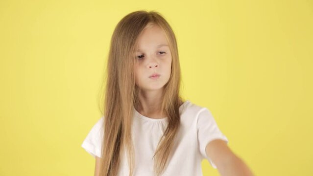 Dissatisfied angry little kid girl in white t-shirt isolated on yellow background studio. Childhood lifestyle concept. Swearing holding palm crossed hands, stop gesture
