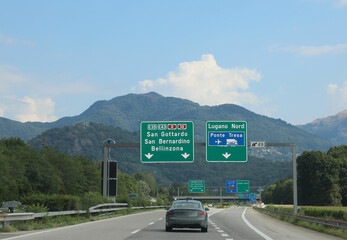 road signs on the motorway with directions to many locations in Switzerland near the Italian border - obrazy, fototapety, plakaty