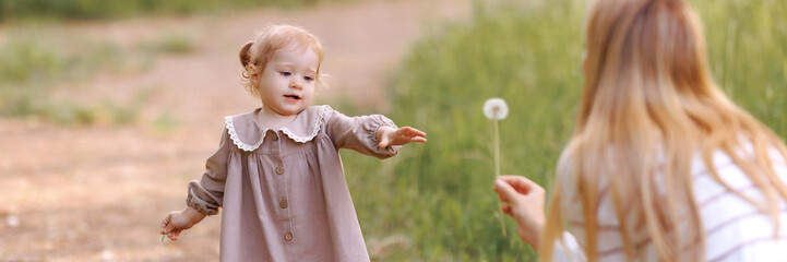 A 2-3 year old blonde child in a light pink dress with a white collar and white shoes goes to her...
