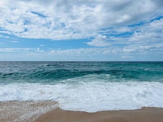 Waved ocean horizon, ocean coastline, sandy shore, splash and foam, cloudy sky, windy