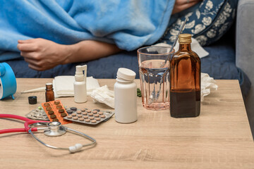 Chory pacjent leży w łóżku w domu otoczony lekami leżącymi na stole