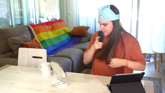 Gay man brushing her long hair in the living room