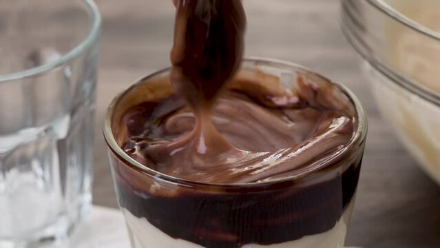 Spoon of a white chocolate vanilla bean pudding served with rich dark chocolate sauce, close-up view