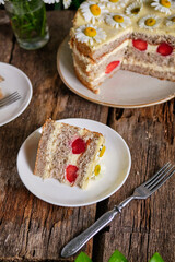 banana cake, vanilla mousse, strawberries, decorated with daisies. 