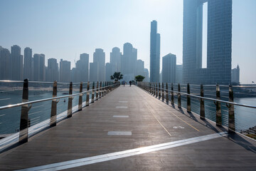 Dubai city silhouette and sea behind the timbered walking terrace bicycle lanes in Dubai blue...