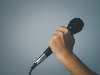 Hold microphone for speaking or singing. On a blurred gray background Copy space