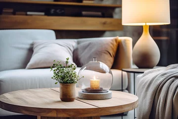Fotobehang Close up of round glass jar with burning candle on rustic wooden coffee table. Lamp on side table near grey sofa. Minimalist loft home interior design of modern living room. © Vadim Andrushchenko