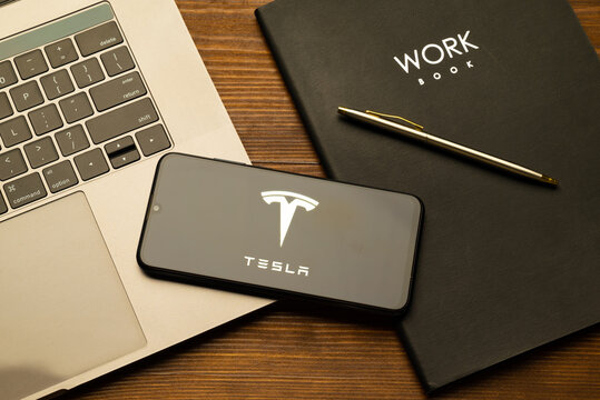 Kyoto city, Japan - July 31, 2023: Logo Tesla on a smartphone near modern laptop on wooden background
