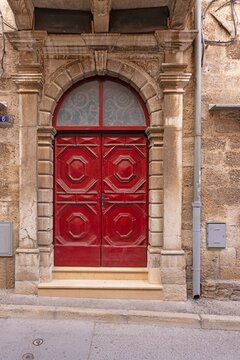 Image of a red entrance door to a residential building with an antique façade