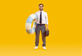 Happy businessman combines business trip and summer holiday. Full body length adult man in office wear with water floatie and briefcase standing isolated on yellow background. Vacation, travel concept - obrazy, fototapety, plakaty