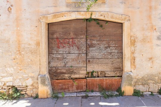 Image of a damaged brown entrance door to a building with an antique façade