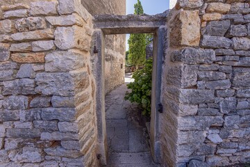 View through an old stone door frame without a door into a backyard of an ancient building