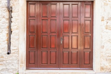 Image of a brown entrance door to a residential building with an antique façade