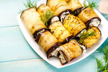 Appetizer of eggplant with cream cheese on a white plate. Keto appetizer of baked eggplant on a blue wooden background. Keto diet. Top view. - Powered by Adobe