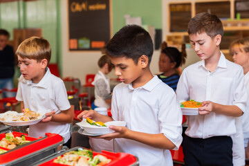 children eat in the school canteen. children stand in line for food in the cafeteria with trays. school nutrition concept