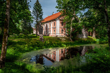 Abandoned Manor House in Kurzeme, Latvia. Stende Manor. View of the manor from the park with reflection in the river.