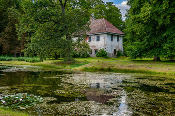 View of the hunting castle through the flower pond. Oldest buildings at the Pope Estate is the old hunting castle that was built in 1653. Latvia, Baltic.